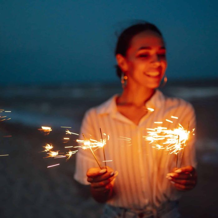Glowing sparkles in hands. Women with Christmas sparklers on nature and twillight sky background.